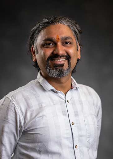 Dr. Raja Khushwah in front of a dark background. He is wearing a grey shirt.